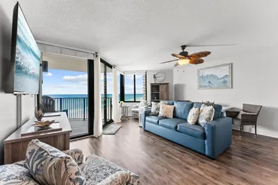 a living room with a blue couch and a view of the ocean at Modern Condo! Free Beach Chairs & Pools by Dolce Vita Getaways PCB in Panama City Beach