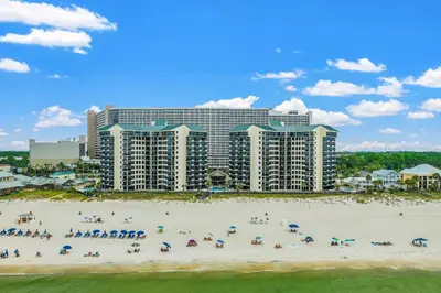a group of people on a beach in front of a hotel at Modern Condo! Free Beach Chairs & Pools by Dolce Vita Getaways PCB in Panama City Beach