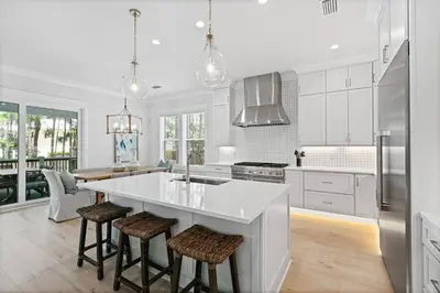 a white kitchen with a large island with bar stools at Golf Cart, Big pool, Bikes, Pets OK, Walk 2 Beach! in Santa Rosa Beach