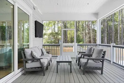 a screened in porch with chairs and a table at Golf Cart, Big pool, Bikes, Pets OK, Walk 2 Beach! in Santa Rosa Beach