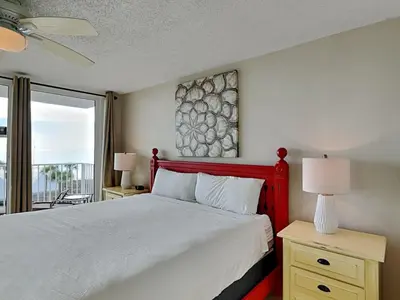 a bedroom with a bed with a red headboard and a window at Dunes of Panama #B301 in Panama City Beach