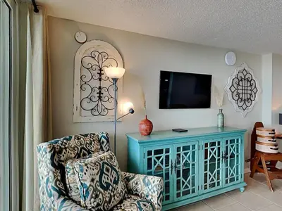 a living room with a chair and a tv at Dunes of Panama #B301 in Panama City Beach