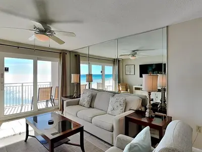 a living room with a white couch and a balcony at Dunes of Panama #D702 in Panama City Beach