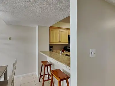 a kitchen with a counter and two stools in it at Dunes of Panama #D702 in Panama City Beach