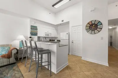 a kitchen with a counter and stools in a room at Shores of Panama Ground Floor Unit 108! No elevators needed and convenient same-floor parking! in Panama City Beach