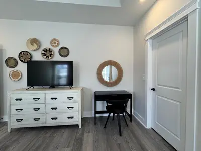 a room with a television on a dresser with a stool at BeaLake House in Panama City Beach