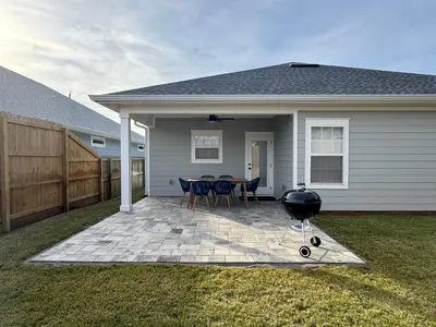 a patio with chairs and a grill in front of a house at BeaLake House in Panama City Beach