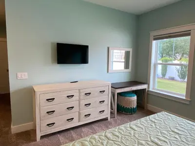 a bedroom with a dresser and a tv on a wall at Reverie Riviera in Panama City Beach