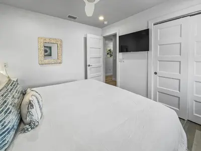 a white bedroom with a large bed and a door at Leeward II 9 l Beachfront Corner Condo l Views of the Water l Sunset Views in Seagrove Beach