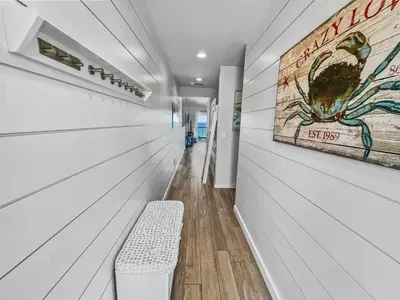 a hallway with a bench and a painting on the wall at Leeward II 9 l Beachfront Corner Condo l Views of the Water l Sunset Views in Seagrove Beach