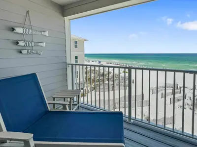 a blue couch on a balcony with a view of the beach at Leeward II 9 l Beachfront Corner Condo l Views of the Water l Sunset Views in Seagrove Beach