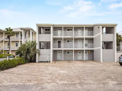 a large white apartment building with a parking lot at Leeward II 9 l Beachfront Corner Condo l Views of the Water l Sunset Views in Seagrove Beach