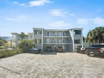 a large building with cars parked in a parking lot at Leeward II 9 l Beachfront Corner Condo l Views of the Water l Sunset Views in Seagrove Beach
