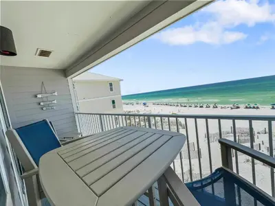 a balcony with a table and chairs and the beach at Leeward II 9 l Beachfront Corner Condo l Views of the Water l Sunset Views in Seagrove Beach