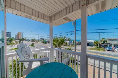 a porch with a chair and a view of a street at Paradise by the Pier l Ocean Views l Dog Friendly l Steps to Pier Park Shopping and Restaurants in Panama City Beach