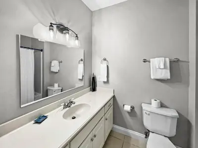 a bathroom with a sink and a toilet and a mirror at Paradise by the Pier l Ocean Views l Dog Friendly l Steps to Pier Park Shopping and Restaurants in Panama City Beach