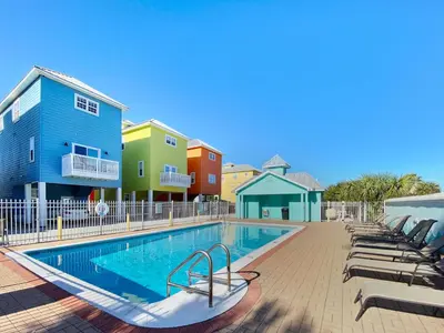 a swimming pool with lounge chairs next to a building at Paradise by the Pier l Ocean Views l Dog Friendly l Steps to Pier Park Shopping and Restaurants in Panama City Beach