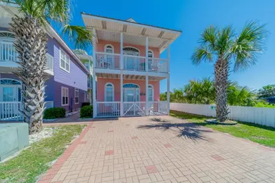 a pink house with palm trees in front of it at Paradise by the Pier l Ocean Views l Dog Friendly l Steps to Pier Park Shopping and Restaurants in Panama City Beach