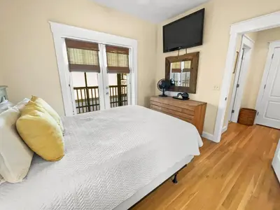 a bedroom with a white bed and a flat screen tv at Mare e Sole l Steps to the Beach l South of 30A l Beachfront Pool l 2 Bikes included in Rosemary Beach
