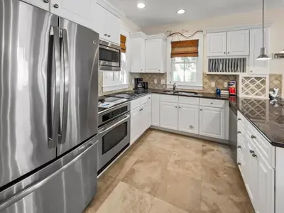 a kitchen with white cabinets and a stainless steel refrigerator at Mare e Sole l Steps to the Beach l South of 30A l Beachfront Pool l 2 Bikes included in Rosemary Beach