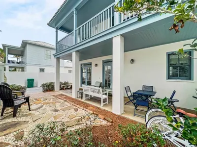 a patio of a house with chairs and a table at Mare e Sole l Steps to the Beach l South of 30A l Beachfront Pool l 2 Bikes included in Rosemary Beach