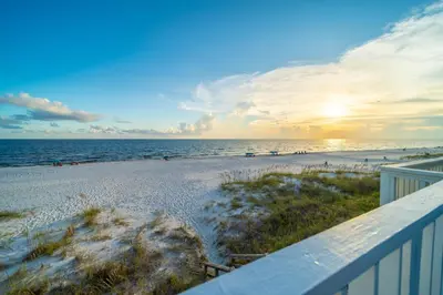 a view of the beach at sunset from a balcony at On the Beach l Beach Front l Steps to the Beach l 2 Bikes Included in Inlet Beach