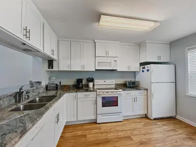 a kitchen with white cabinets and a sink and a refrigerator at On the Beach l Beach Front l Steps to the Beach l 2 Bikes Included in Inlet Beach