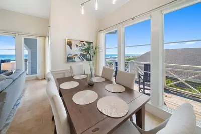 a dining room with a table and chairs and windows at Paradise Loft l Luxury Beach Front Condo l Amazing Views in Santa Rosa Beach