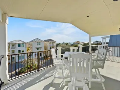 a patio with white chairs and a table on a balcony at Pompano Palace l Bike or Walk to Rosemary l Gulf Views l Community Pool in Rosemary Beach