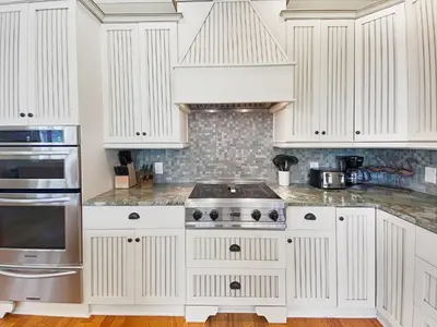 a kitchen with white cabinets and a stove at Pompano Palace l Bike or Walk to Rosemary l Gulf Views l Community Pool in Rosemary Beach