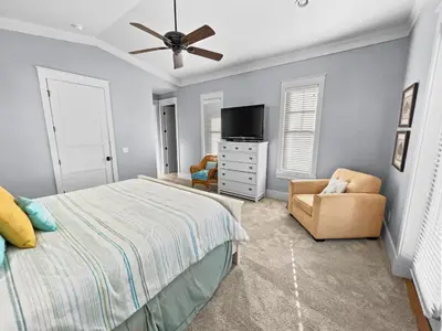 a bedroom with a bed and a tv and a chair at Pompano Palace l Bike or Walk to Rosemary l Gulf Views l Community Pool in Rosemary Beach