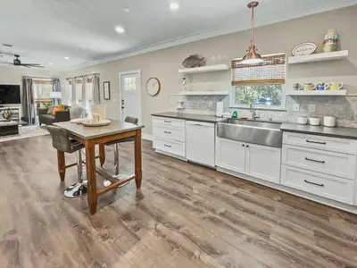 a kitchen with white cabinets and a sink and a table at Pinewood l Inlet Beach l Dog Friendly in Inlet Beach