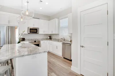 a kitchen with white cabinets and a marble counter top at Pura Vida l 5 Bedroom l Private Pool l Walk to Beach l Panama City Beach in Panama City Beach
