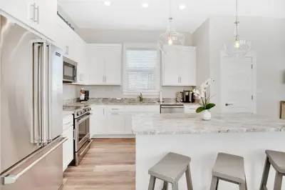 a kitchen with white cabinets and a large island with stools at Pura Vida l 5 Bedroom l Private Pool l Walk to Beach l Panama City Beach in Panama City Beach