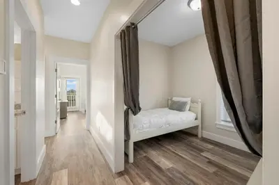 a white room with a bed and a hallway at Pura Vida l 5 Bedroom l Private Pool l Walk to Beach l Panama City Beach in Panama City Beach