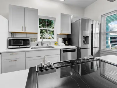 a kitchen with white cabinets and a stainless steel refrigerator at Sand Piper l 4 Minute Walk to the Beach l Inlet Beach in Inlet Beach
