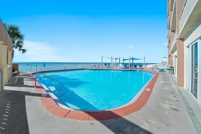 a swimming pool with the ocean in the background at Sea Horsey Retreat l Community Heated Pool l Amazing Ocean Views l Beachfront Condo in Panama City Beach