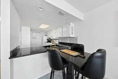 a kitchen with black counter chairs and white cabinets at Seacrest 8 l Beachfront l Bike to Alys and Rosemary Beach in Seacrest