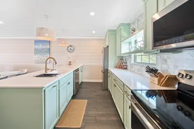 a kitchen with green cabinets and a sink at Shoreline Breeze l Steps to the Beach l Beautiful views from 2nd and 3rd balconies in Inlet Beach