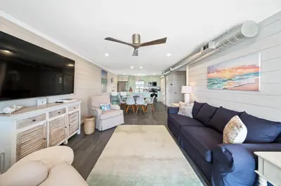 a living room with a blue couch and a tv at Shoreline Breeze l Steps to the Beach l Beautiful views from 2nd and 3rd balconies in Inlet Beach