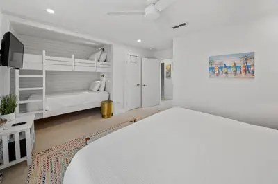 a white bedroom with a bed and a bunk bed at Shoreline Breeze l Steps to the Beach l Beautiful views from 2nd and 3rd balconies in Inlet Beach