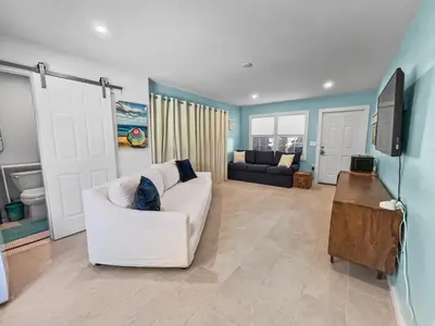 a living room with a white couch and a television at Shoreline Breeze l Steps to the Beach l Beautiful views from 2nd and 3rd balconies in Inlet Beach