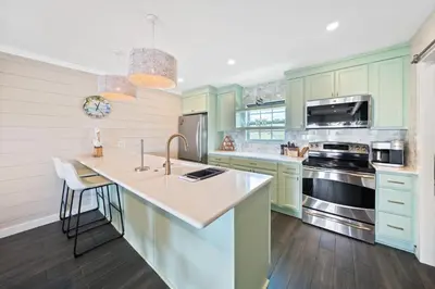 a kitchen with green cabinets and a white counter top at Shoreline Breeze l Steps to the Beach l Beautiful views from 2nd and 3rd balconies in Inlet Beach