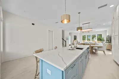 a kitchen with white walls and a blue island at Shore Thing l Private Pool l Walk to the beach l Bike to Seaside l Brand New Construction and Decor in Santa Rosa Beach