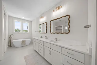 a white bathroom with a tub and a sink and a mirror at Shore Thing l Private Pool l Walk to the beach l Bike to Seaside l Brand New Construction and Decor in Santa Rosa Beach