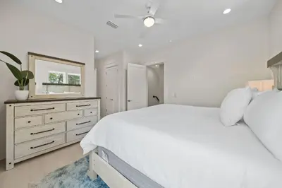a white bedroom with a large bed and a mirror at Shore Thing l Private Pool l Walk to the beach l Bike to Seaside l Brand New Construction and Decor in Santa Rosa Beach