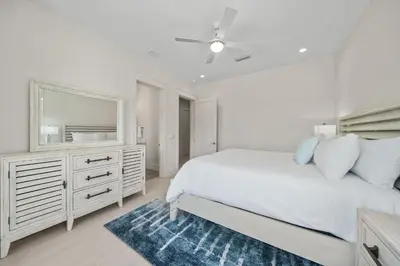 a white bedroom with a bed and a mirror at Shore Thing l Private Pool l Walk to the beach l Bike to Seaside l Brand New Construction and Decor in Santa Rosa Beach