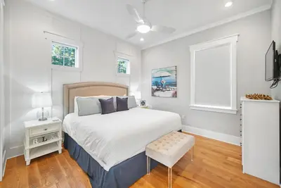 a white bedroom with a bed and a chair at Someday Came l 4 Bikes and Beach Towels l Community Pool in Inlet Beach