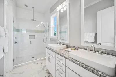 a white bathroom with two sinks and a shower at Someday Came l 4 Bikes and Beach Towels l Community Pool in Inlet Beach