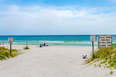 a beach with a sign in the sand and the ocean at Shoreline Townhomes 10 l Steps to the Beach l Beautiful views from 2nd and 3rd balconies in Inlet Beach